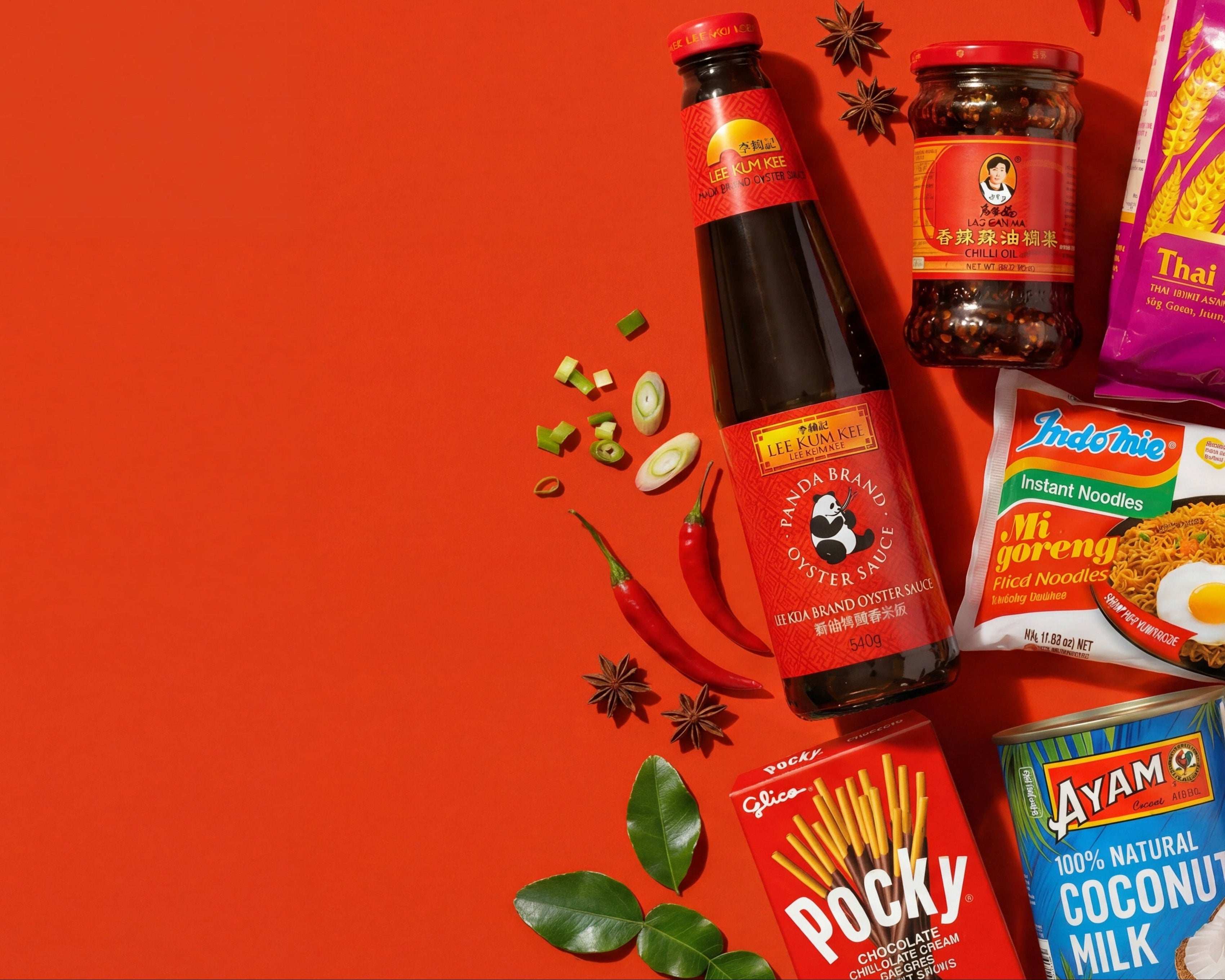 Assorted food products including a bottle of sauce, packets of rice, Spam, and other snacks on an orange background.